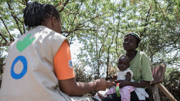 Mitarbeiterin von Aktion gegen den Hunger spricht mit einer Mutter über die Ernährung ihres Kindes in Kenia.