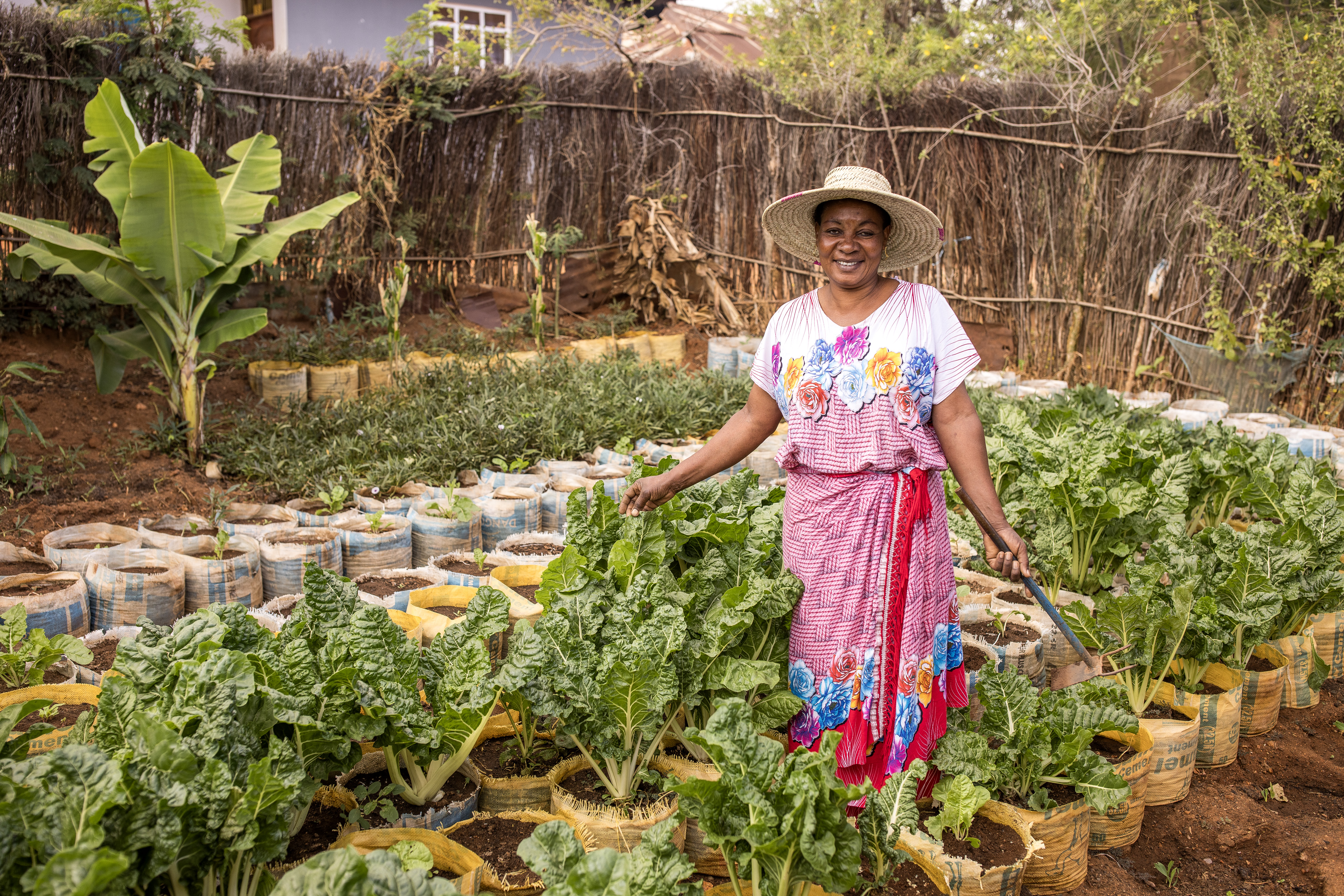Salama Madinda steht in ihrem Gemüsegarten in Tansania und lächelt in die Kamera.