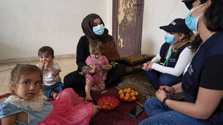 Dana, eine syrische Geflüchtete, mit ihren Kindern Nagham (11 Monate), Akram (11 Monate) und Nour (4 Jahre), im Gespräch mit dem Team von Aktion gegen den Hunger im Südlibanon, Mai 2022.
