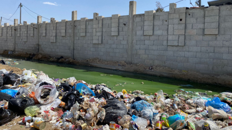 Müll vor einer Mauer im Gazastreifen rund um eine grüne Pfütze.