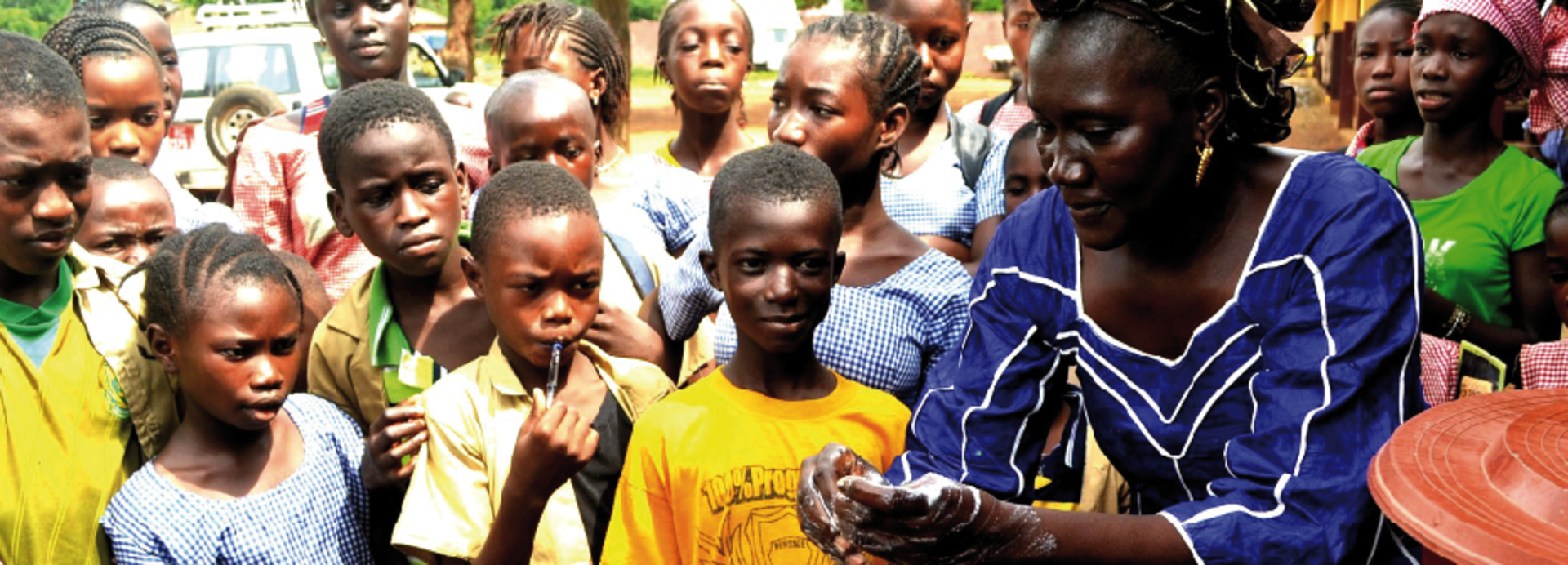 Frau erklärt in Guinea den umstehenden Menschen etwas.