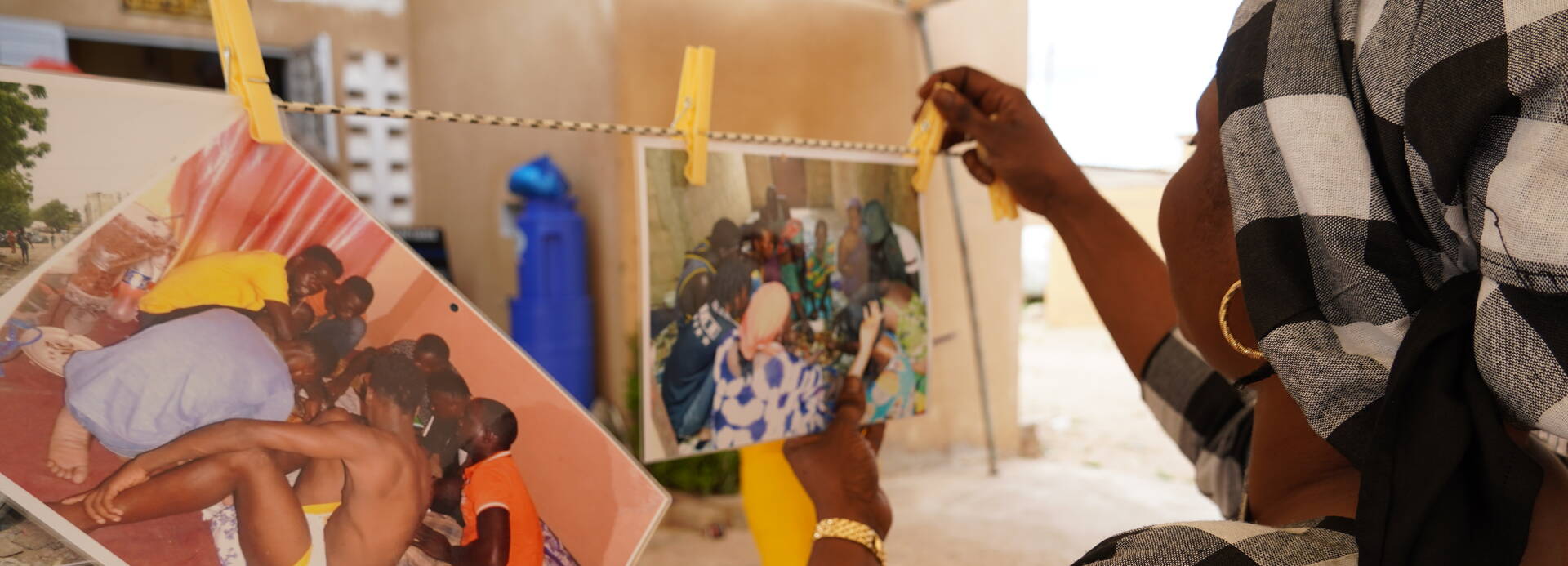 Eine Frau aus dem Senegal hängt selbstgeschossene Fotos auf einer Leine auf