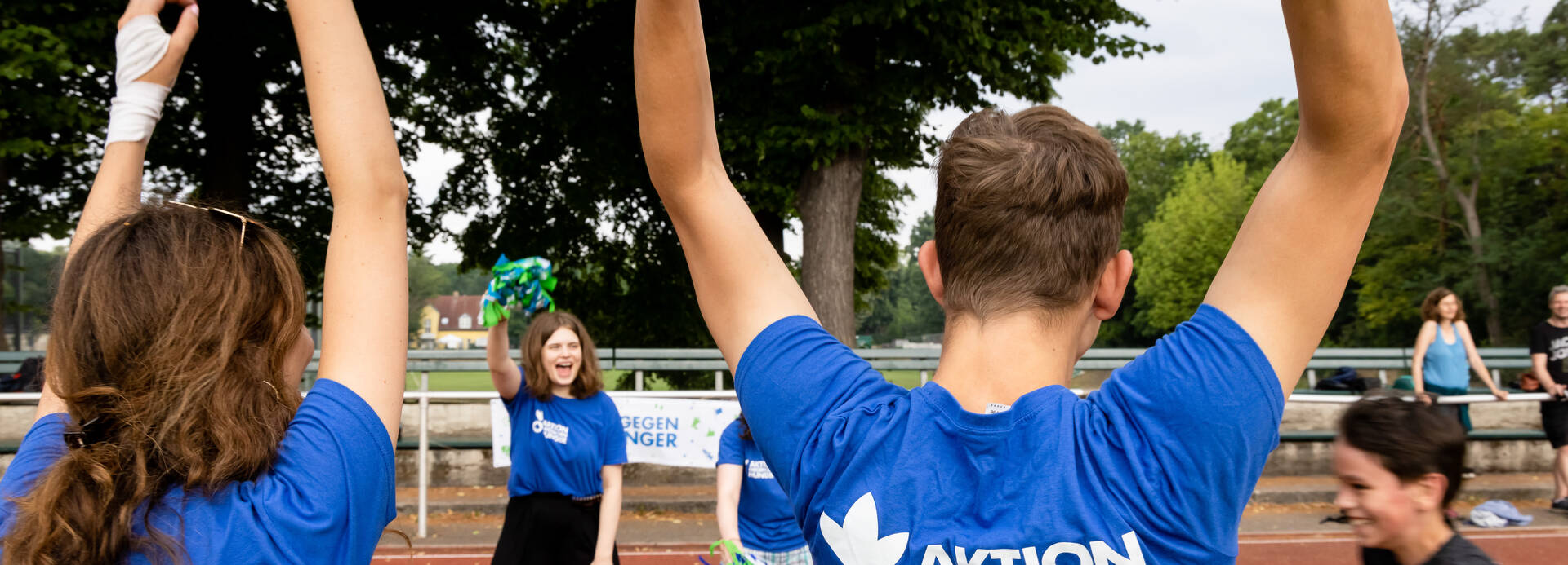 Mitarbeitende feuern Kinder beim Spendenlauf an