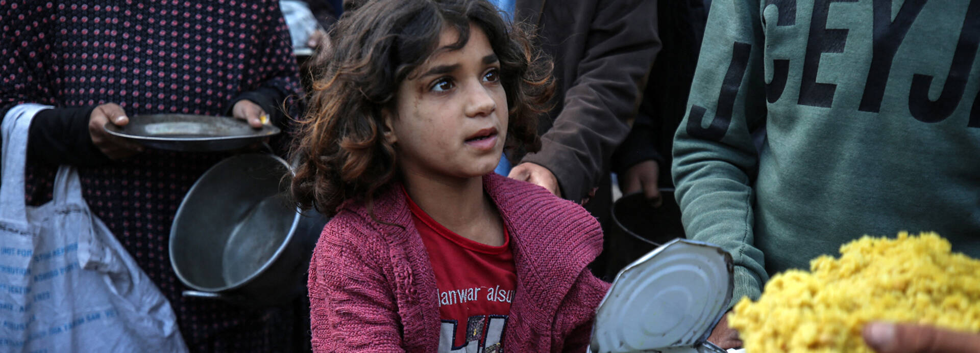 Ein Mädchen im Gazastreifen hält eine geöffnete Dose mit Nahrung in der Hand.
