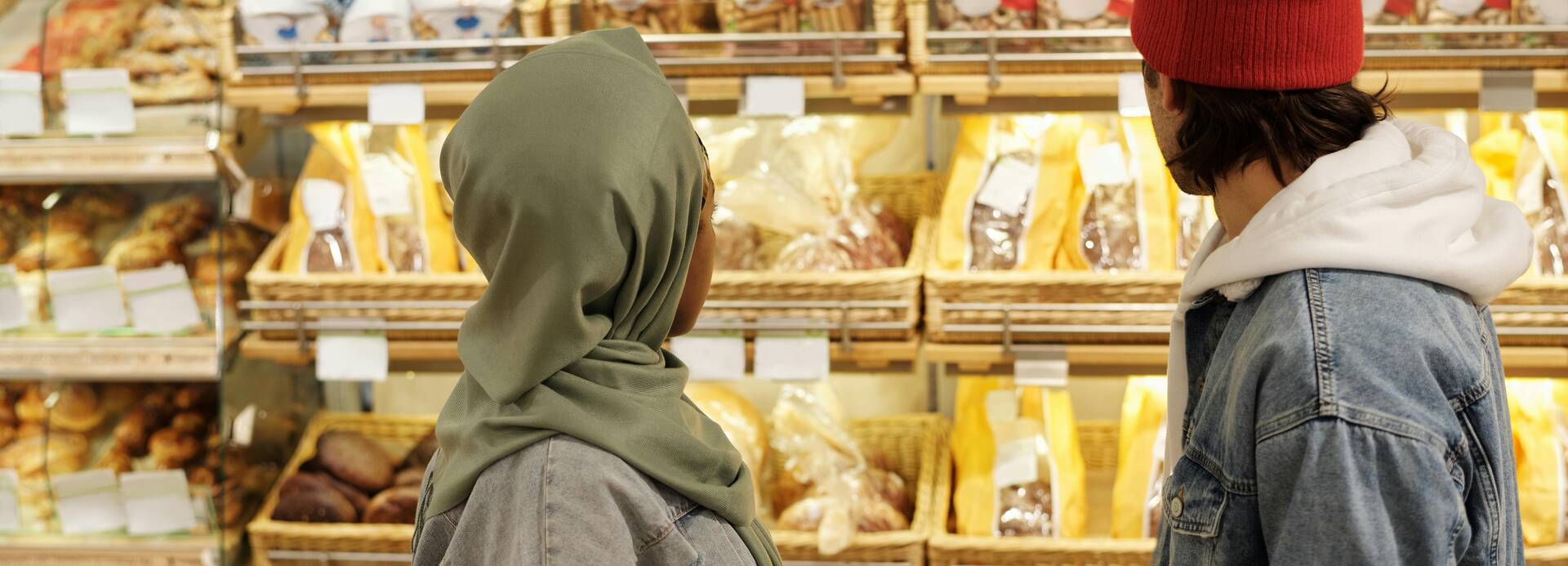 Zwei Menschen stehen vor einem Brotregal in einem Supermarkt.