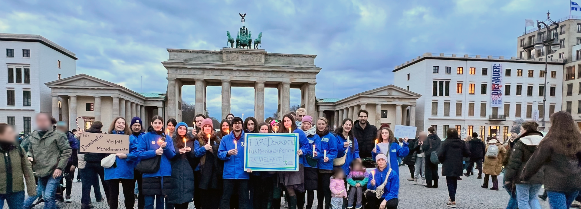 Mitarbeitende von Aktion gegen den Hunger stehen mit Schildern für Demokratie und Menschenrechte vor dem Brandenburger Tor.