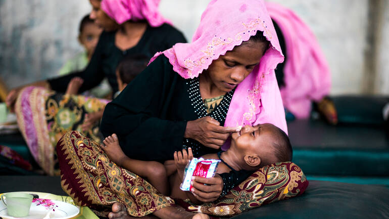 In einem unserer Behandlungszentren in Bangladesch gibt eine Mutter ihrem Kind nahrhafte nahrhafte Erdnusspaste, sog. Plumpy'nut.