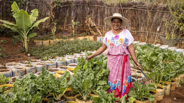 Salama Madinda steht in ihrem Gemüsegarten in Tansania und lächelt in die Kamera. 