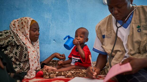 Ein kleines Kind ist zusammen mit der Mutter in Behandlung bei einem Arzt von Aktion gegen den Hunger.