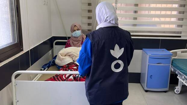 Eine Mitarbeiterin von Aktion gegen den Hunger spricht mit einer jungen Mutter im Al Awda Krankenhaus in Jabalia, Gaza