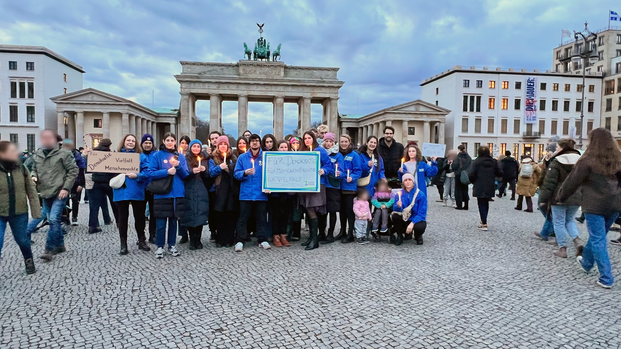 Mitarbeitende von Aktion gegen den Hunger stehen mit Schildern für Demokratie und Menschenrechte vor dem Brandenburger Tor.